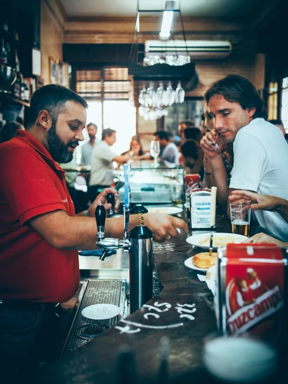 client et serveur accoudé au comptoir de las columnas à seville, voyage en espagne